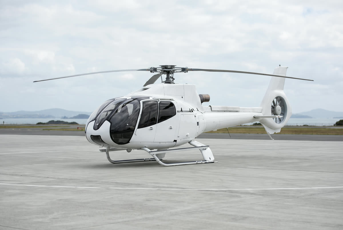 A Airbus H130 helicopter on a helipad, unmarked, seen from the front left